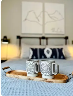 two coffee mugs sitting on a tray on a bed at Pet-friendly Walk-Up Condo with Pool & Hot tub! in Canmore