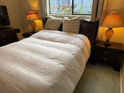 a bedroom with a white bed with two lamps and a window at Sweet Home in Aldergrove