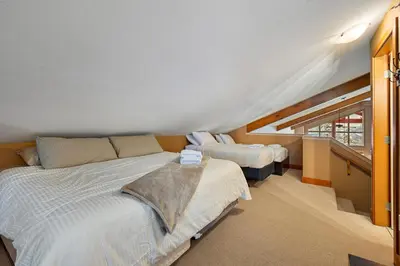 a bedroom with two beds and a staircase at Blackrock 6 in Big White