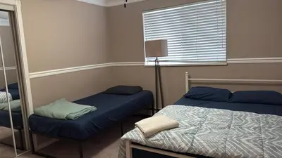 a bedroom with two beds and a mirror at Surrey- Delta Budget Guest House - Private Rooms & Suites, Free Parking & Fast Wi-Fi in Surrey