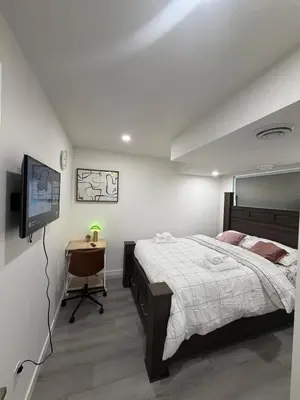 a bedroom with a bed and a television and a table at Brand New 1 Bedroom Basement Suite in Southwest in Edmonton