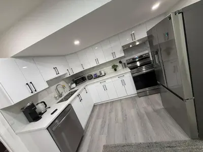 a kitchen with white cabinets and stainless steel appliances at Brand New 1 Bedroom Basement Suite in Southwest in Edmonton