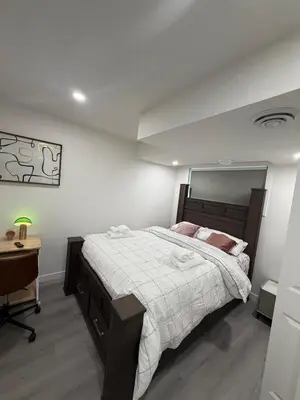a bedroom with a large bed and a desk at Brand New 1 Bedroom Basement Suite in Southwest in Edmonton