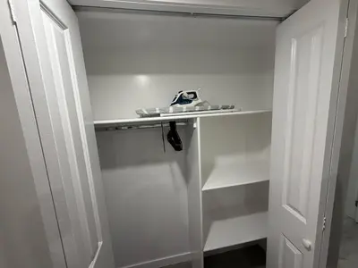 a white closet with a shelf and a door at Brand New 1 Bedroom Basement Suite in Southwest in Edmonton