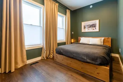 a bedroom with a bed and two windows at Peaks & Pines by Fernie Central Reservations in Fernie