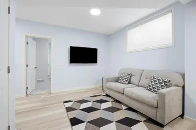 a living room with a couch and a flat screen tv at Cozy 2 Bedroom Private Basement Suite SW Calgary in Calgary