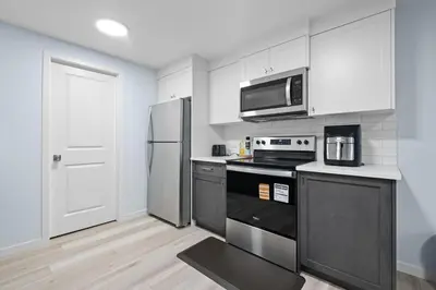 a kitchen with a stove and a refrigerator at Cozy 2 Bedroom Private Basement Suite SW Calgary in Calgary