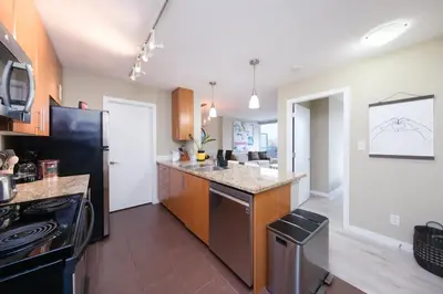 a kitchen with a black refrigerator and a counter at Modern Central Location with Pool Sauna & Jacuzzi in Vancouver
