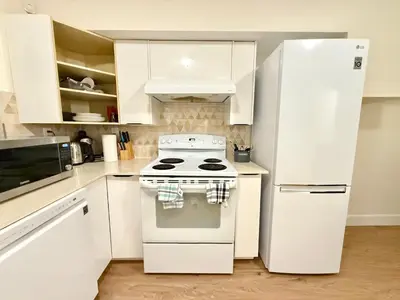 a white kitchen with a stove and a refrigerator at Private Guest Suite, Two Parking Spaces in Maple Ridge District Municipality