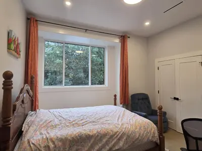 a bedroom with a bed and a window and a chair at Luxury Suite in New Villa in Surrey