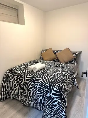 a bed with black and white sheets and pillows at Comfort 2 BR Vancouver! in Vancouver
