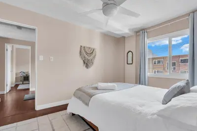 a white bedroom with two beds and a window at 2B 17 Ave King Suite in Calgary