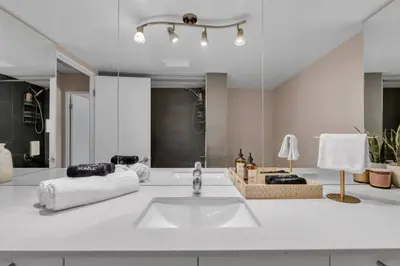 a white bathroom with a sink and a mirror at 2B 17 Ave King Suite in Calgary