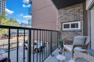 a balcony with a chair and a table with a glass of wine at 2B 17 Ave King Suite in Calgary