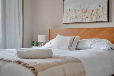a bedroom with a white bed with a wooden headboard at 2B 17 Ave King Suite in Calgary