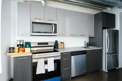 a kitchen with white cabinets and stainless steel appliances at Cozy Downtown Retreat with Stunning River Views in Calgary
