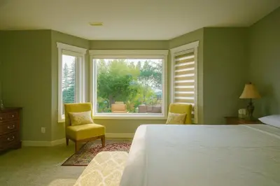 a bedroom with a bed and two chairs and a window at Shiraz Place in Calgary