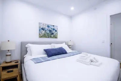 a white bed with a blue pillow and towels on it at 431 Frontier in Calgary