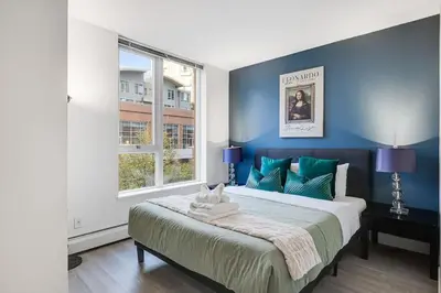 a bedroom with a large bed with blue walls at Stylish 2BR Downtown Condo By Arena Free Parking in Vancouver