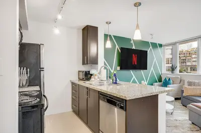 a kitchen with a counter top and a living room at Stylish 2BR Downtown Condo By Arena Free Parking in Vancouver