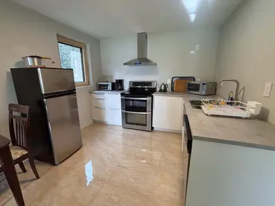a kitchen with a stainless steel refrigerator and white cabinets at Coastal Drift Sooke in Sooke