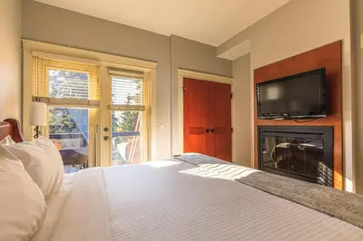 a bedroom with a bed and a tv and a fireplace at Evergreen at Solara Resort in Canmore