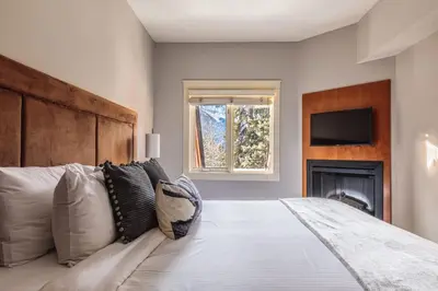 a bedroom with a large bed with a tv on the wall at Evergreen at Solara Resort in Canmore