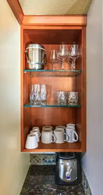 a cupboard filled with dishes and glasses and a blender at Evergreen at Solara Resort in Canmore