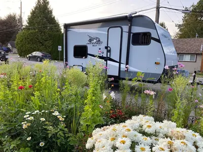 a trailer parked in a field of flowers at Warm new Jayco trailer with comfy queen bed in Aldergrove