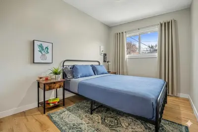 a bedroom with a bed with blue sheets and a window at Entire Home - 2 Separate Units in Calgary
