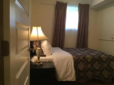 a bedroom with a bed with a lamp and a window at Modern 2 BR Vacation Home Near West Edmonton Mall in Edmonton