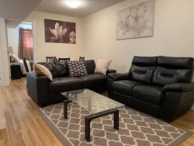 a living room with a black leather couch and a table at Modern 2 BR Vacation Home Near West Edmonton Mall in Edmonton