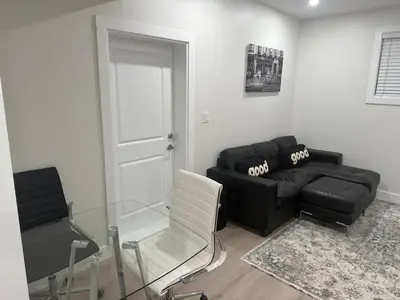 a living room with a black couch and a chair at The ideal place for professionals in Prince George