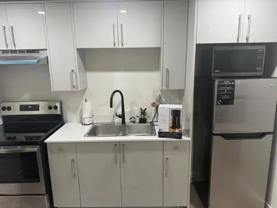 a white kitchen with a sink and a refrigerator at The ideal place for professionals in Prince George