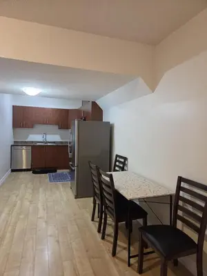 a kitchen with a table and chairs and a refrigerator at Modern 2 Bedroom Suite Private & Fully Furnished in Prince George