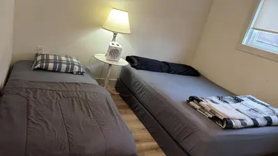 two beds in a room with a lamp on a table at Vancouver Downtown Apartment - Walk to SkyTrain & BC Place, Free Parking in Vancouver