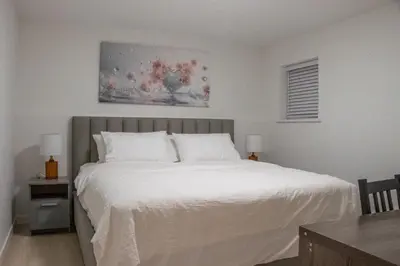 a bedroom with a white bed and a painting on the wall at 4615 Inverness Street Vancouver King And Queen size 2 Bedrooms Suite with Private Entry in Vancouver
