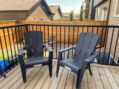 two black chairs on a deck with a fence at Modern 2BR Suite with Private Yard in Calgary