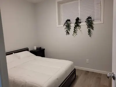 a bedroom with a bed and two plants on the wall at Modern 2BR Suite with Private Yard in Calgary