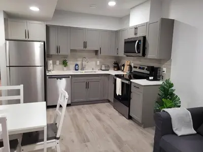 a kitchen with stainless steel appliances and gray cabinets at Modern 2BR Suite with Private Yard in Calgary