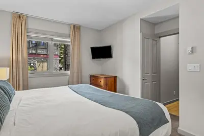 a bedroom with a bed and a tv and a window at Cedar and Stone - 2 Bed 2 Bath Condo with Heated Pool and Hot Tub in Canmore