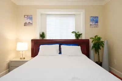 a bedroom with a large white bed with blue pillows at Cozy Room with Private Washroom in Central Location in Vancouver