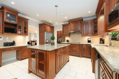 a large kitchen with wooden cabinets and granite counter tops at Cozy Room with Private Washroom in Central Location in Vancouver