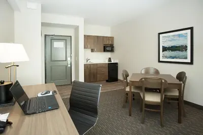 a living room with a table and a kitchen at Wingate by Wyndham Calgary Airport in Calgary