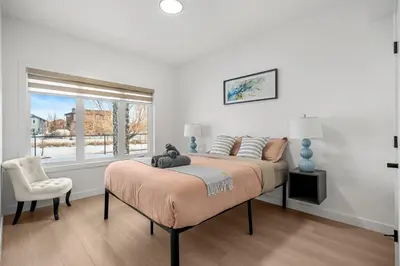 a bedroom with a bed with a teddy bear on it at Waterfront 1BR Suite Private and Modern and Queen Bed in Airdrie