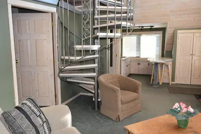 a spiral staircase in a room with a chair and a table at Retreat Wilderness Inn in Nimpo Lake