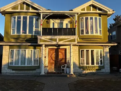 a yellow house with a front door with a balcony at private 1br guest suite Vancouver in Vancouver