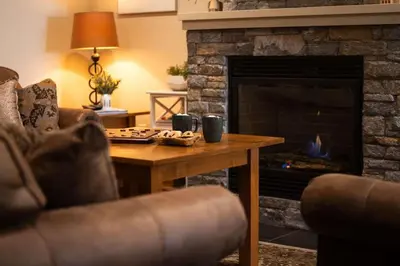 a living room with a table and a fireplace at Arnica Chalet 2bd 2bath Ski In Out Silver Star in Vernon