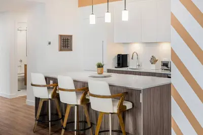 a kitchen with a island with white counter tops at Dt Spacious and Vibrant | Kng Bed| Outdoor patio in Calgary