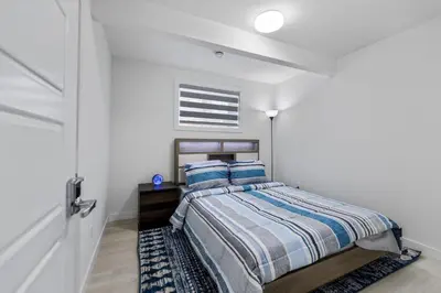 a bedroom with a bed in a white room at Brand New 3 Bedroom, 2 Washroom, Kitchen and Ensuite in Chestermere